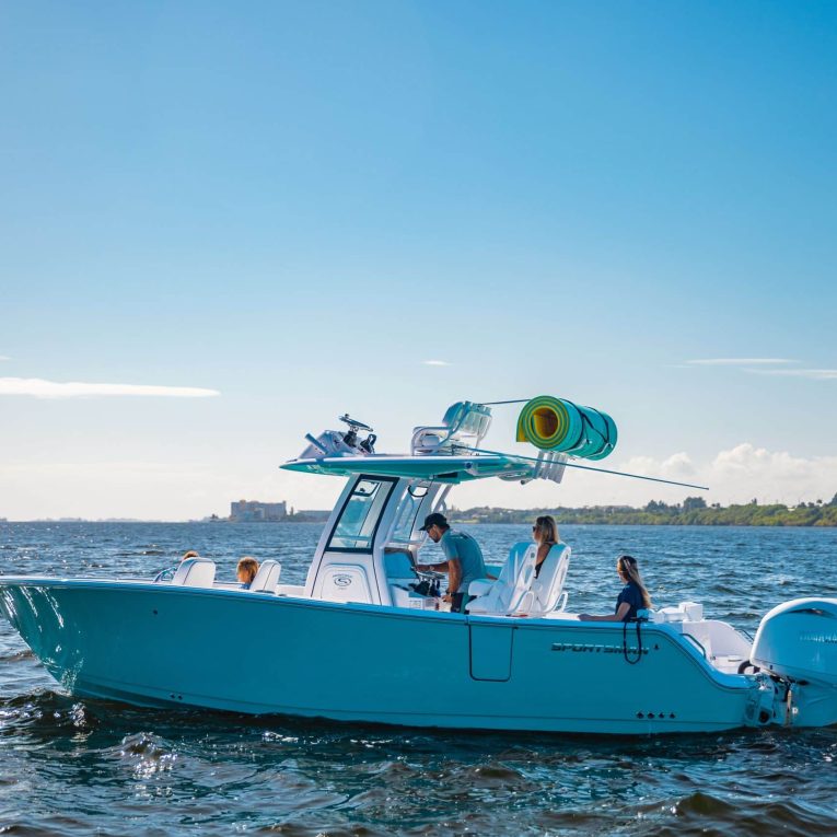 mantaracks-12 (1) Man driving a boat with two passengers seated at the front and two at the back, featuring a floating mat storage rack on the roof of the boat.