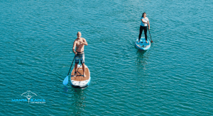 Image of a man and woman on a paddleboard enjoying the sea.
