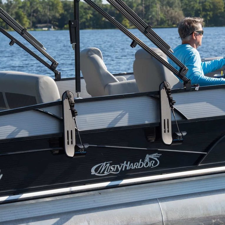 PSE_8726 Man driving boat with paddleboard storage on side.