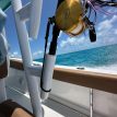 A fishing rod and reel mounted on the front of a boat, secured with a Manta Racks Rod & Reel Leash.
