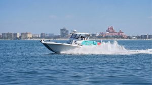 White and teal center console boat running across blue water along the Florida coast